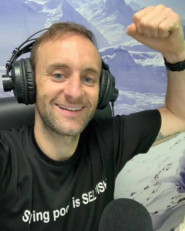 Joe Doyle posing with his hand raised in the middle of his podcasting session 